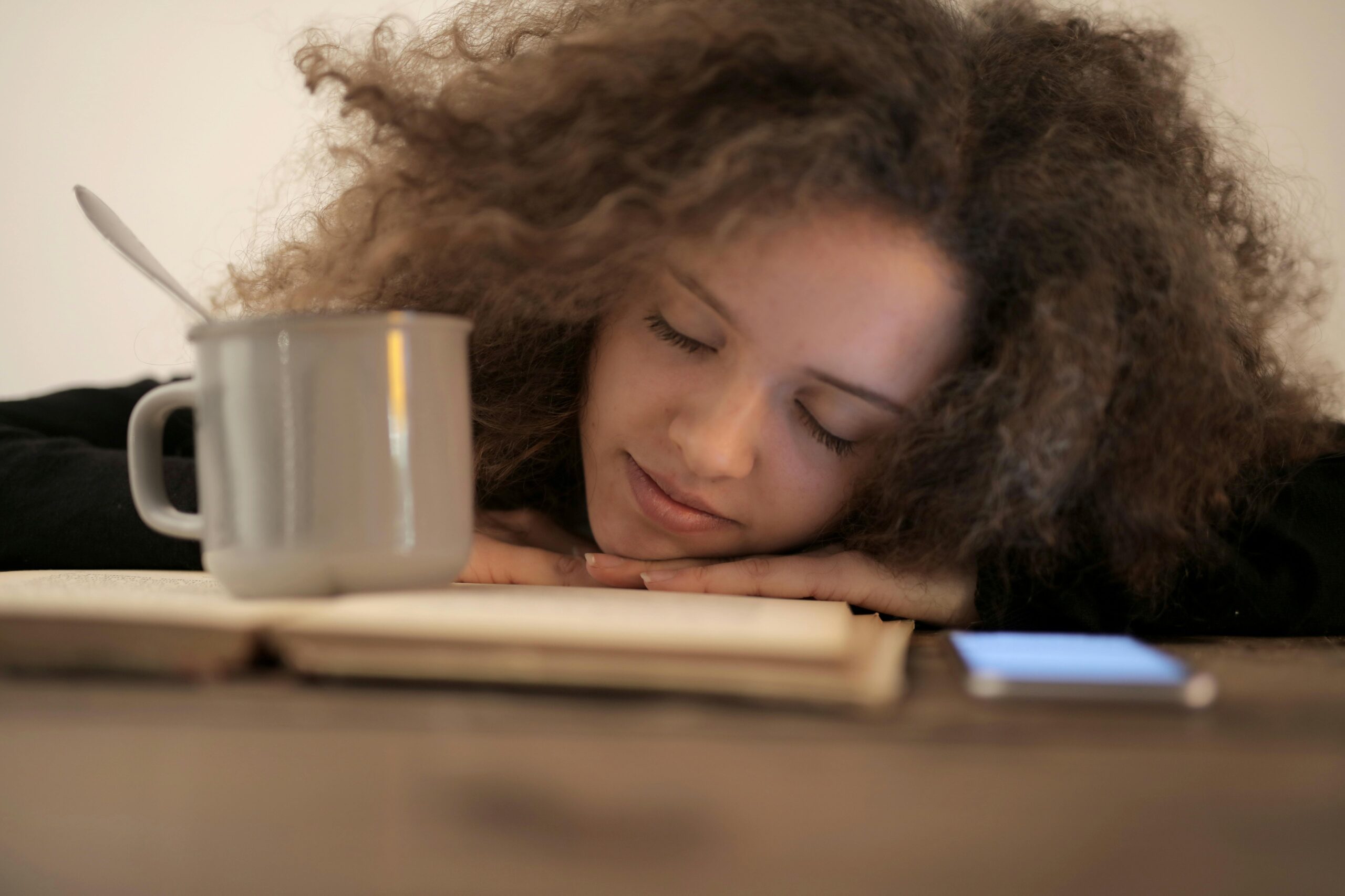 woman with her eyes closed and her head down on book slightly smiling